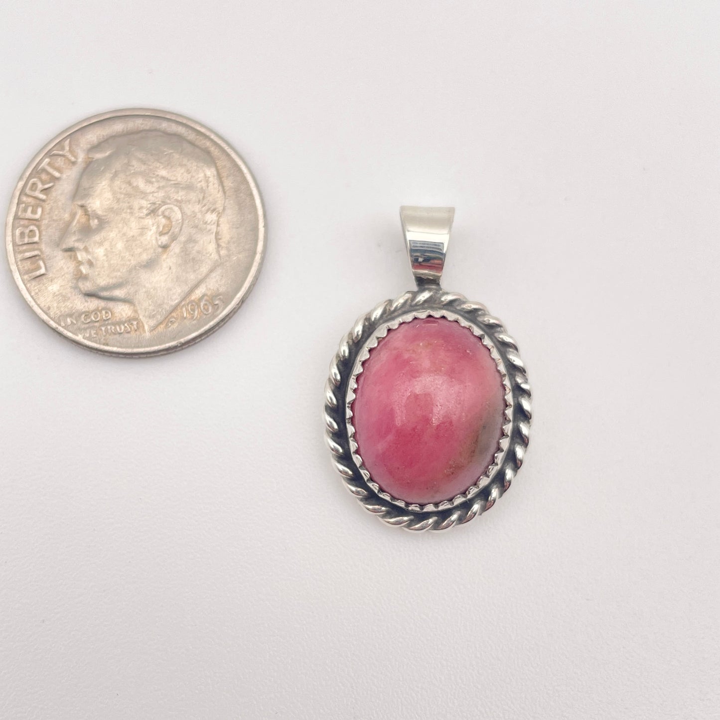 rhodonite stone pendant with Sterling silver frame show with a dime for scale