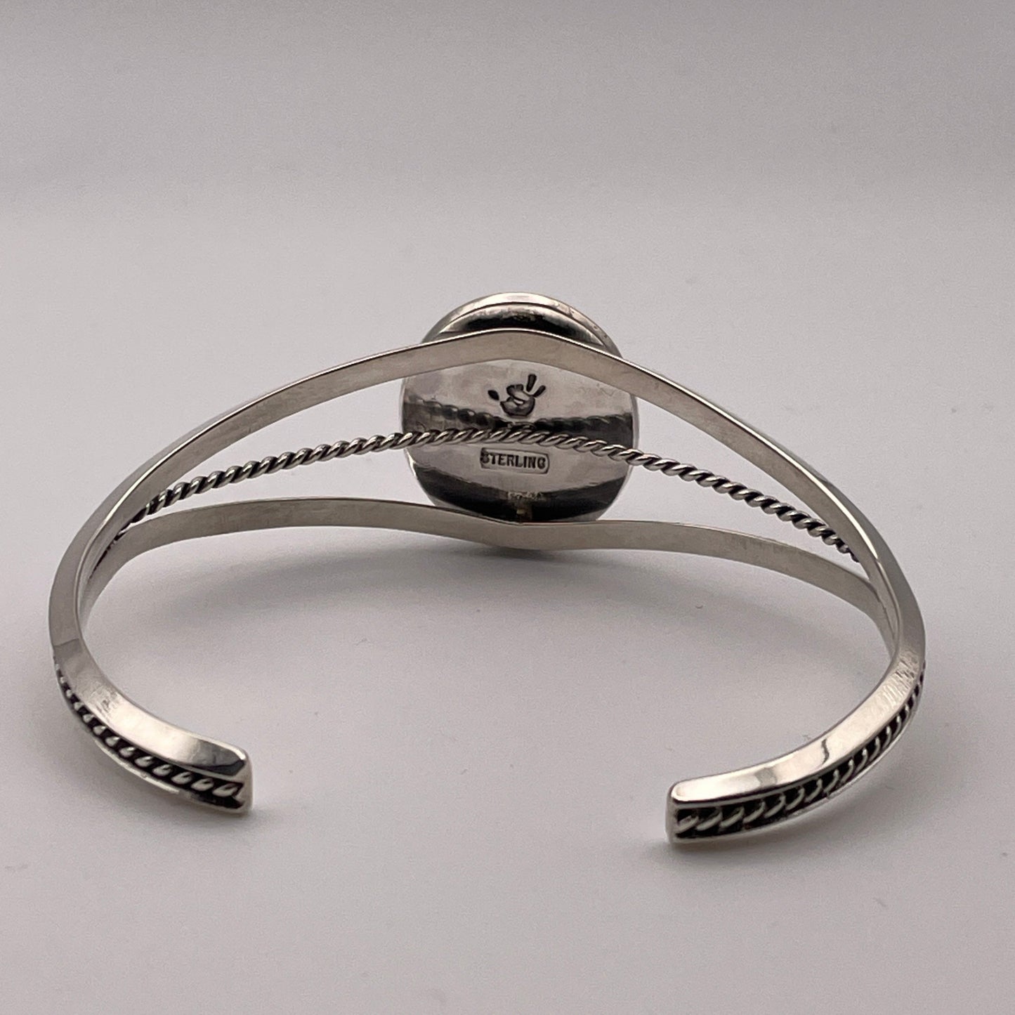 back view of sterling silver cuff bracelet with triangle wire design showing STERLING stamp and artist's stamp