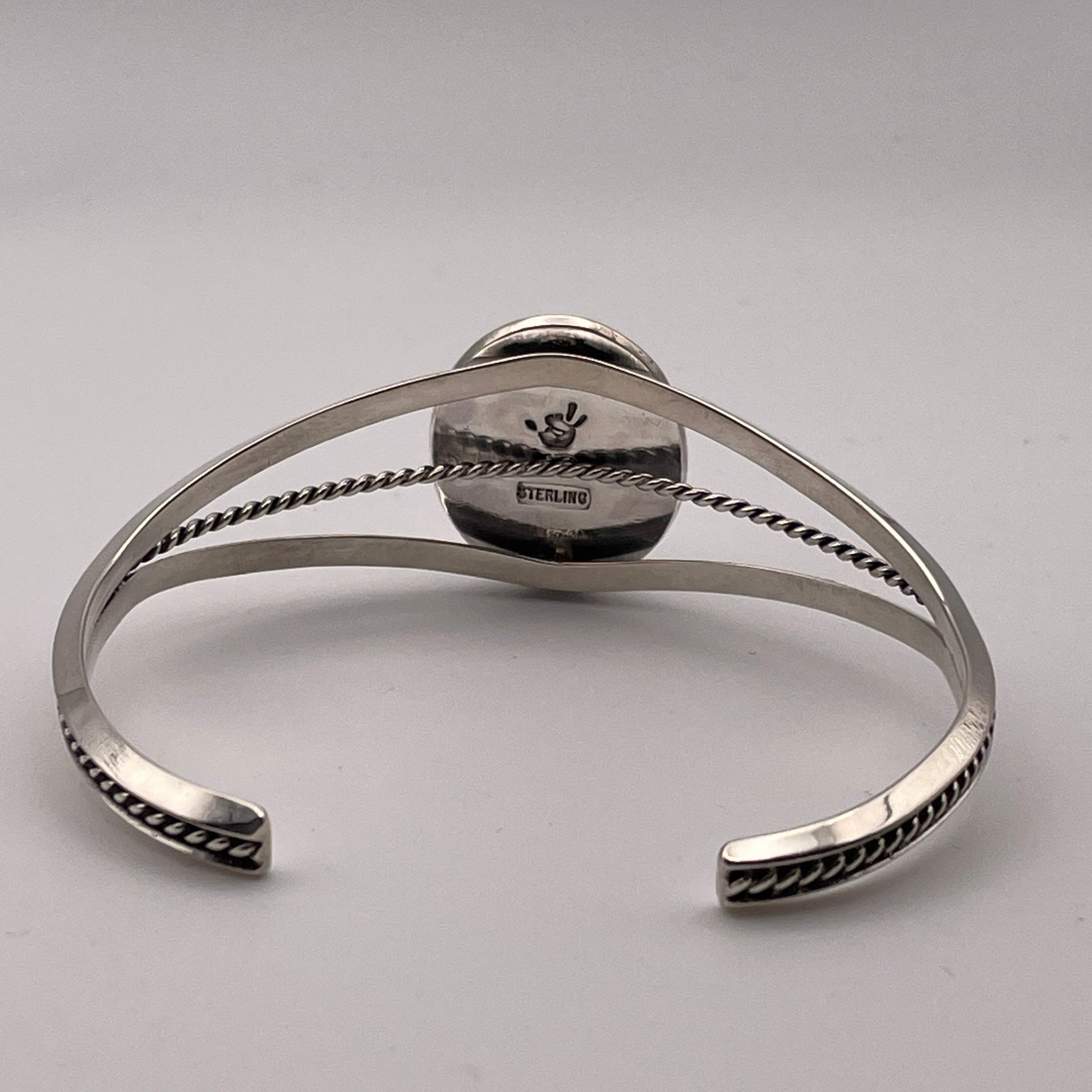 back view of sterling silver cuff bracelet with triangle wire design showing STERLING stamp and artist's stamp