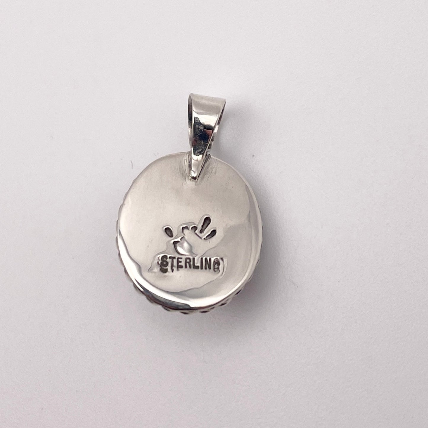 Reverse side of Sterling Silver and rhodonite pendant with STERLING stamp and artist's stamp