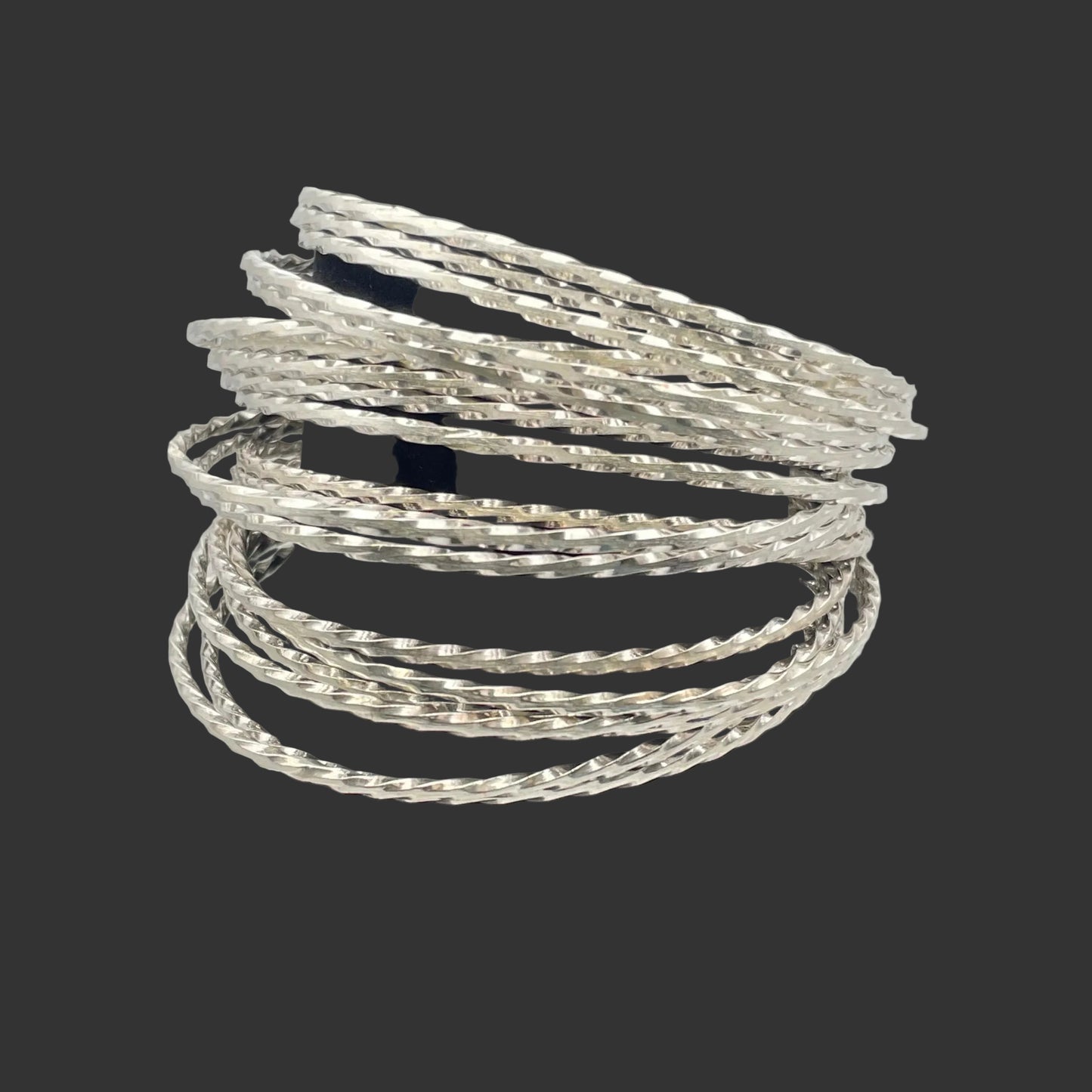 A stack of Sterling Silver bangle bracelets shown on a black stand